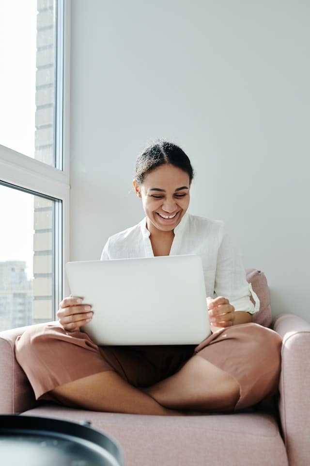 woman smiling on a chair with her computer